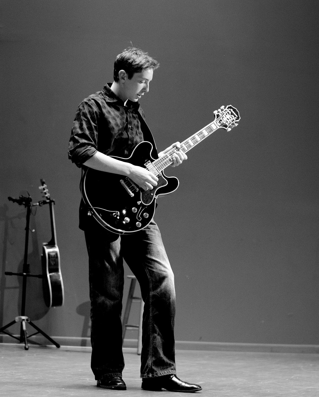 Guitarist leaning into a hollow-body electric guitar